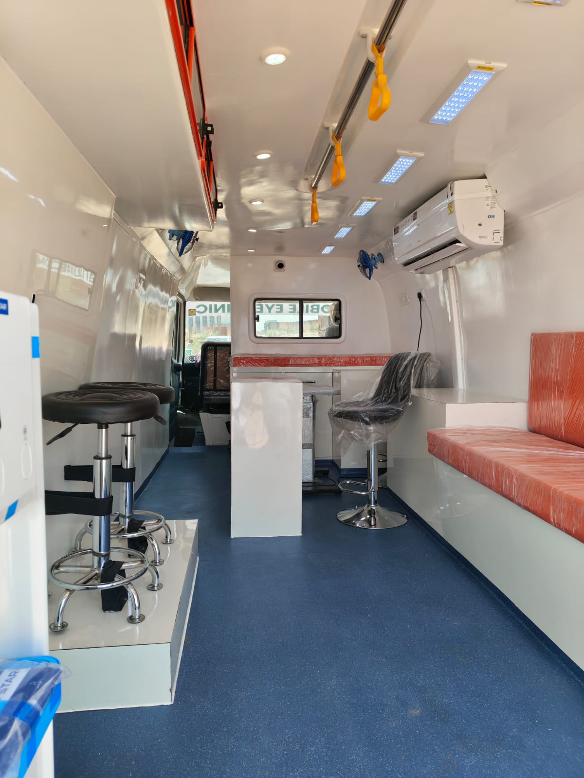 Mobile eye clinic van interior with examination stools and refraction bench